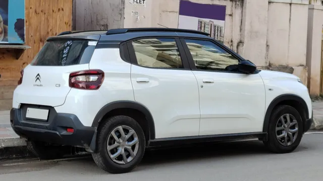 Citroën C3 branco com teto preto visto de traseira três-quartos, estacionado na rua